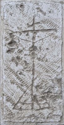 une plaque en pierre sur laquelle est gravée une croix, fixée à un mur