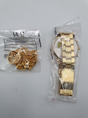 a gold watch and a gold chain on a white table