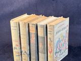 plusieurs vieux livres pour enfants alignés les uns à côté des autres sur un fond bleu
