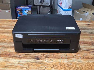 a black printer sitting on top of a wooden table next to boxes