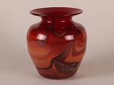 a red vase with a swirly design on it
