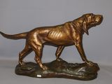 bronze statue of a dog on a rock on a white background