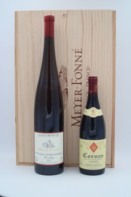 deux bouteilles de vin posées devant une caisse en bois sur une table