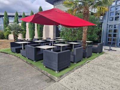 tables and chairs with red umbrellas in front of a building