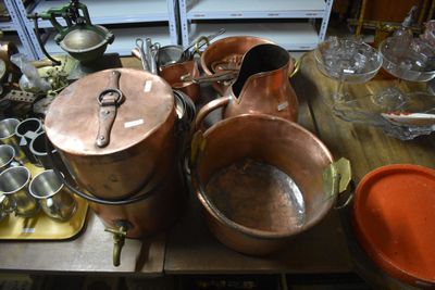 many copper pots and pans on a table