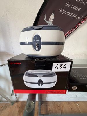 une friteuse à air chaud blanche et noire posée sur une boîte