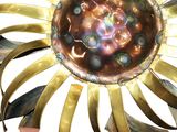 someone is holding a metal object with a flower design on it