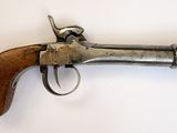 un vieux pistolet avec une poignée en bois sur une surface blanche