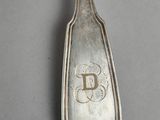 silver spoon with the letter d on it sitting on top of a table