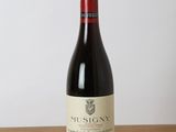 the bottle of red wine is sitting on a wooden table