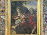 tableau représentant une femme tenant un bébé dans ses bras, dans un cadre doré, accroché à un mur en pierre
