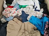 un carton rempli de vêtements et des vêtements par terre