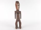 une vieille statue en bois représentant un homme avec un visage et des jambes
