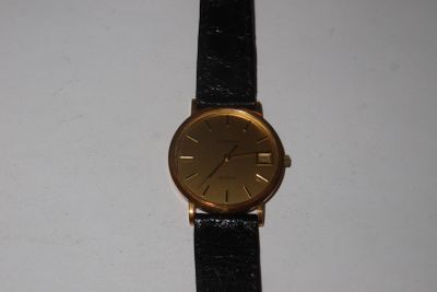 une photo d'une montre en or montée sur un bracelet en cuir noir