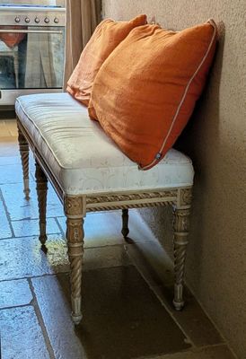 a bench with two orange pillows on it in front of a window