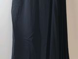 a black skirt hanging on a hanger in front of a white wall