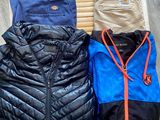 Plusieurs vestes et pantalons sont suspendus sur un portant en bois