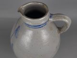 a white and blue vase with a handle on a table