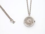 une image représentant une montre de poche en argent avec sa chaîne, posée sur une surface blanche