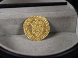 une image représentant une pièce d'or posée dans une boîte sur une table
