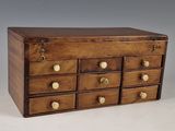 a small wooden box with many drawers on it