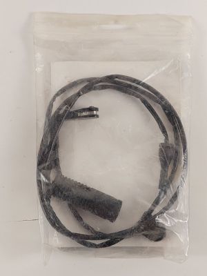 un cordon noir dans un sac en plastique posé sur une surface blanche