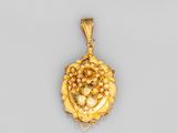 un pendentif en or orné d'une grappe de raisin au centre