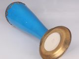 a blue vase with a gold rim sitting on a white surface