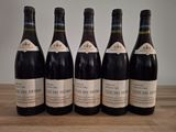 six bottles of wine are lined up on a wooden table