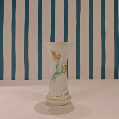 a white vase sitting on a table with a blue and white striped wall behind it