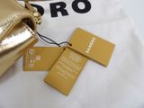 a gold bag with a tag on it sitting next to a t - shirt