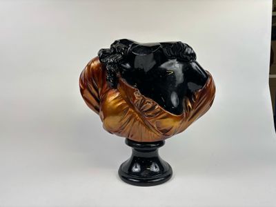 un buste d'homme noir et doré posé sur un socle