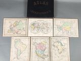 six cartes du monde posées sur une table, à côté d'une boîte noire