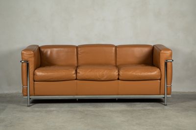 an image of a brown leather couch sitting on top of a cement floor