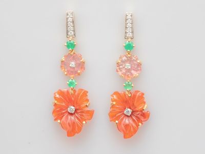 une paire de boucles d'oreilles en forme de fleurs orange et vertes sur fond blanc