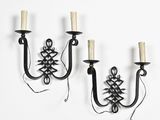 two black iron wall sconces with candle holders on a white wall