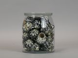 a glass jar filled with black and white shells