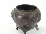 a small bronze pot with a handle on a stand