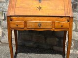 a small wooden desk with a drawer on it in front of a stone wall