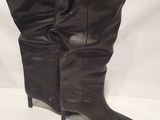 pair of black leather boots sitting on top of a white surface
