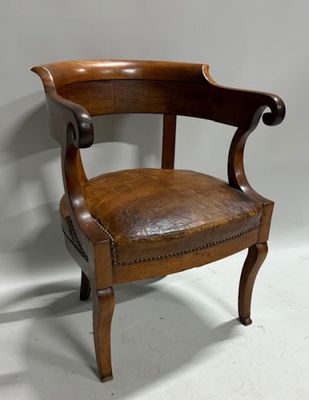 une vieille chaise en bois avec une assise en cuir, posée sur un sol blanc
