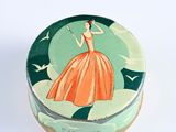 a small tin box with a woman in a dress on it