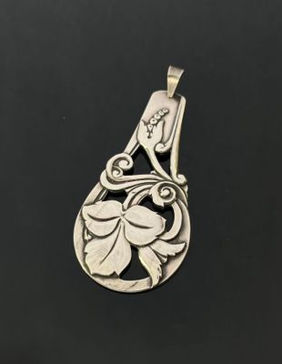 a silver pendant with a flower design on it