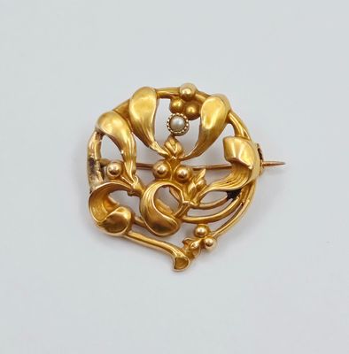 une broche en or ornée d'une perle au centre