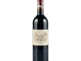 the bottle of red wine is sitting on a white surface