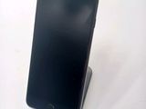 a black cell phone sitting on a stand on a table