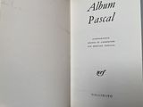 an open book with a hand holding it in front of a white wall