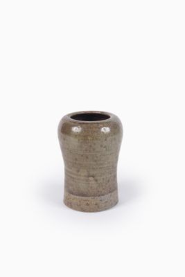 un vase marron muni d'une poignée en bois, posé sur une surface blanche