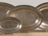 three silver plates are sitting on a table with a wooden stand