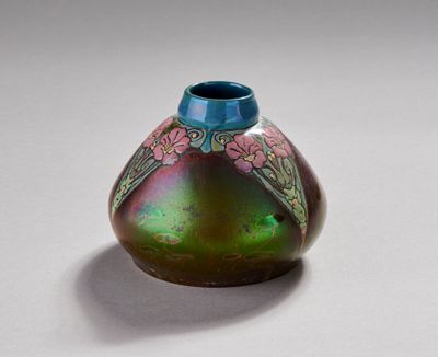 un vase violet et vert orné de fleurs, posé sur un fond blanc